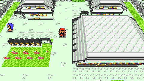 Pallet Town as a voxel diorama on a real PSP: two gabled houses with tiled roofs, a large lab building, carved bushes, flowers, an NPC in blue and the player standing on the path between them, in warm per-tile color.